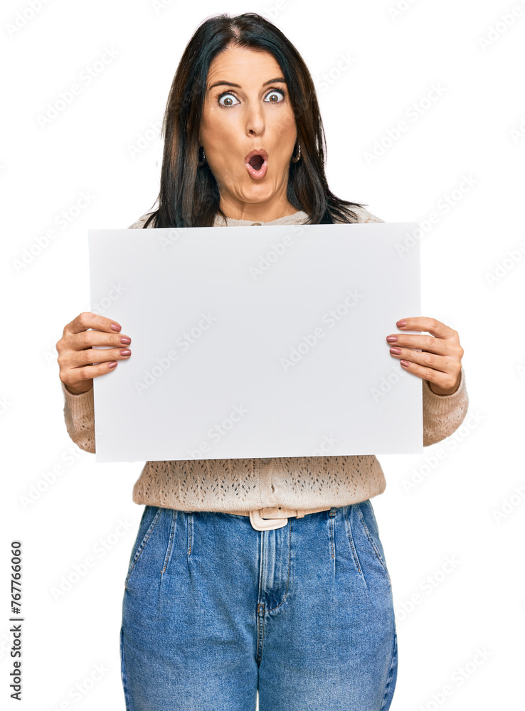 Middle age brunette woman holding blank empty banner scared and amazed with open mouth for surprise, disbelief face Middle age brunette woman holding blank empty banner scared and amazed with open mouth for surprise, disbelief face