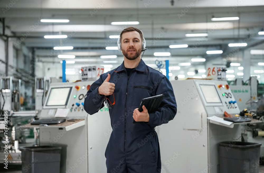 Showing thumb up. Factory worker is indoors with hard hat Showing thumb up. Factory worker is indoors with hard hat