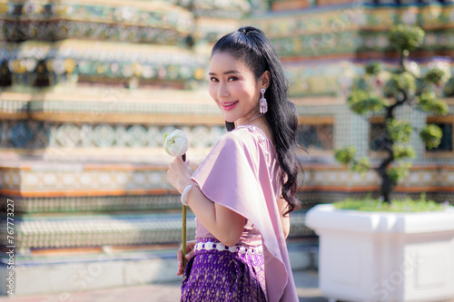 Portrait of a beautiful woman wearing a traditional Thai dress smiling gracefully standing in a temple of Thailand