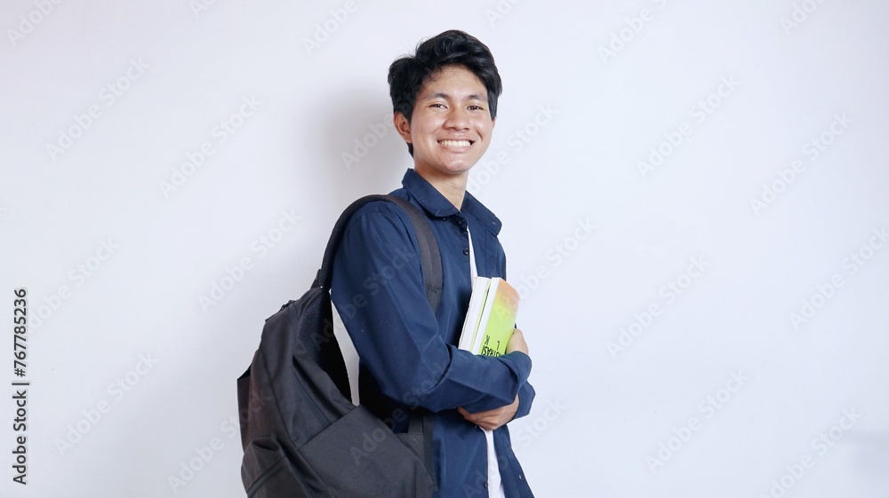 Handsome young Asian male student carrying a bag and carrying a book in hand isolated white background Handsome young Asian male student carrying a bag and carrying a book in hand isolated white background