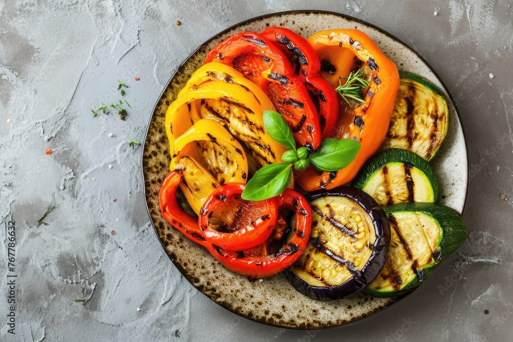Grilled colorful vegetables on plate over grey background.