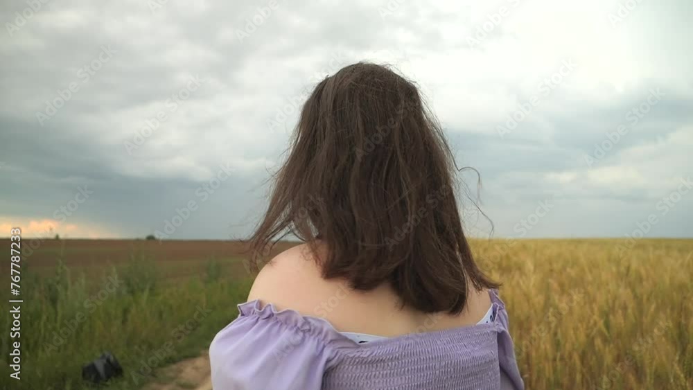 A girl in a dress runs near a field of wheat. Cloudy day. Wavy hair A girl in a dress runs near a field of wheat. Cloudy day. Wavy hair