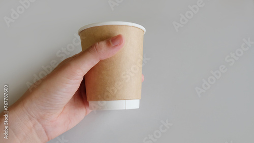 Hand holding a brown disposable paper cup. photo