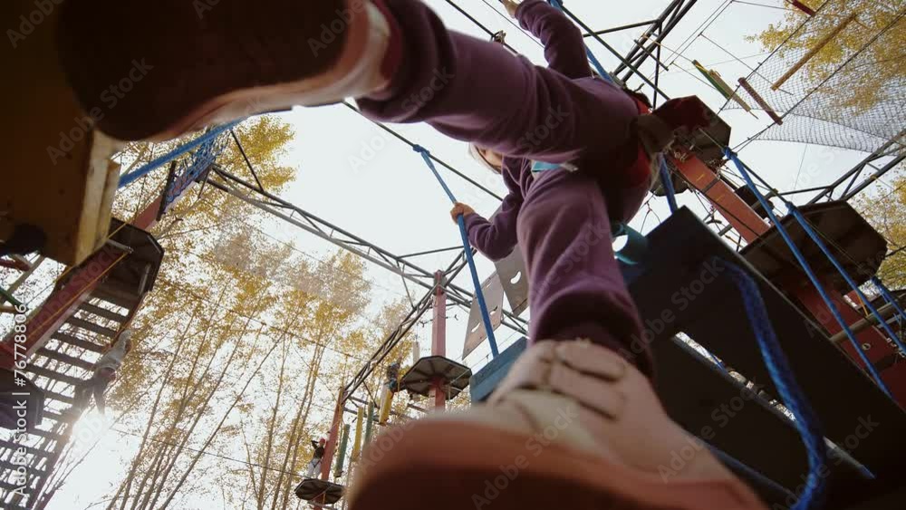 Little girl trying take step but stumbles and slides off in rope park ...