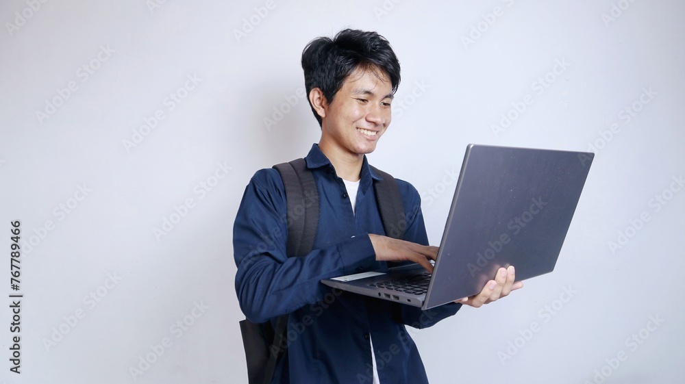 Young handsome Asian man is happy holding a laptop Young handsome Asian man is happy holding a laptop