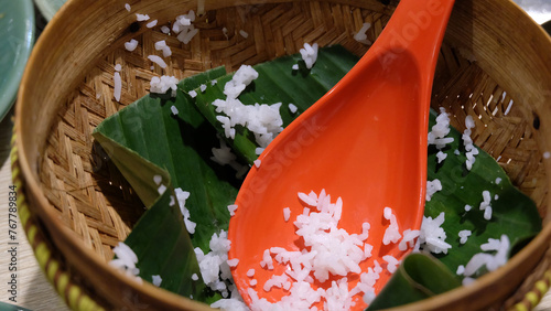 An empty serving basket with banana leaf and some leftover cooked white rice, with an orange rice ladle.