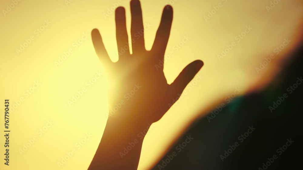 hand of happy girl at sunset with glittering golden light. sunset between the hands of a girl. this happy girl stretches her hand to the sun. girl silhouette dream stretches out her hand to the sun