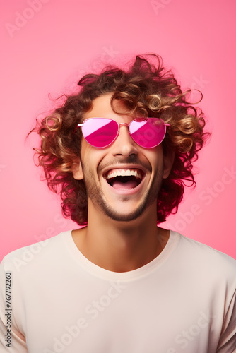 Young man with curly hair wearing pink sunglasses on pink background  © jimenezar