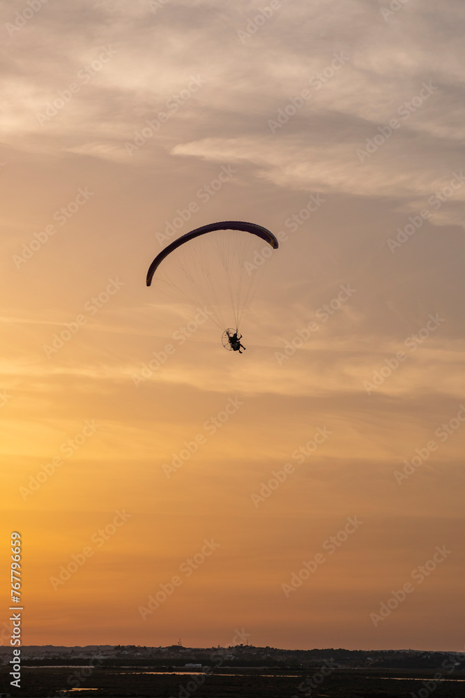 A paraglider or paramotor flying during a beautiful sunset over the beach. Real Photo