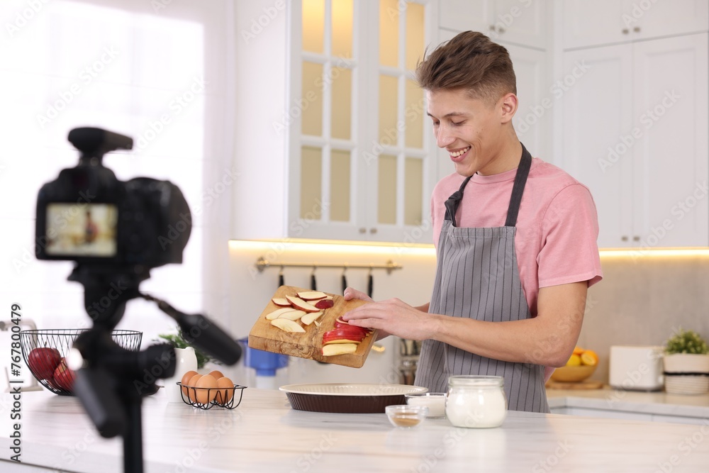 Smiling food blogger cooking while recording video in kitchen Smiling food blogger cooking while recording video in kitchen