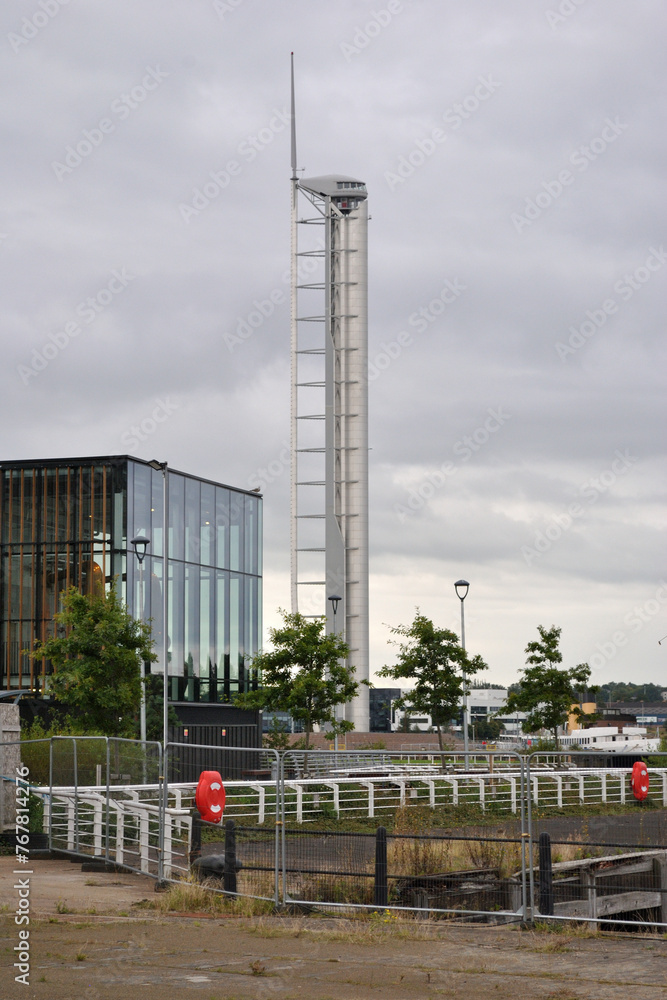 Tall Modernist Metal Tower beside New Building seen from Below Tall Modernist Metal Tower beside New Building seen from Below