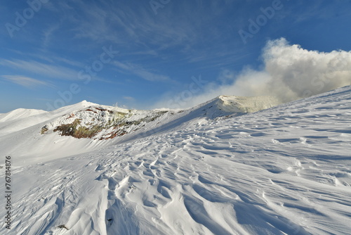 Smoke rising from winter landscape snow-capped Mt. Tokachi volcano, Hokkaido, Japan photo