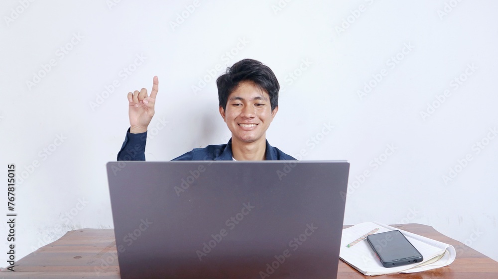 young asian male student happy and relaxed with hands pointing up getting ideas studying on laptop young asian male student happy and relaxed with hands pointing up getting ideas studying on laptop