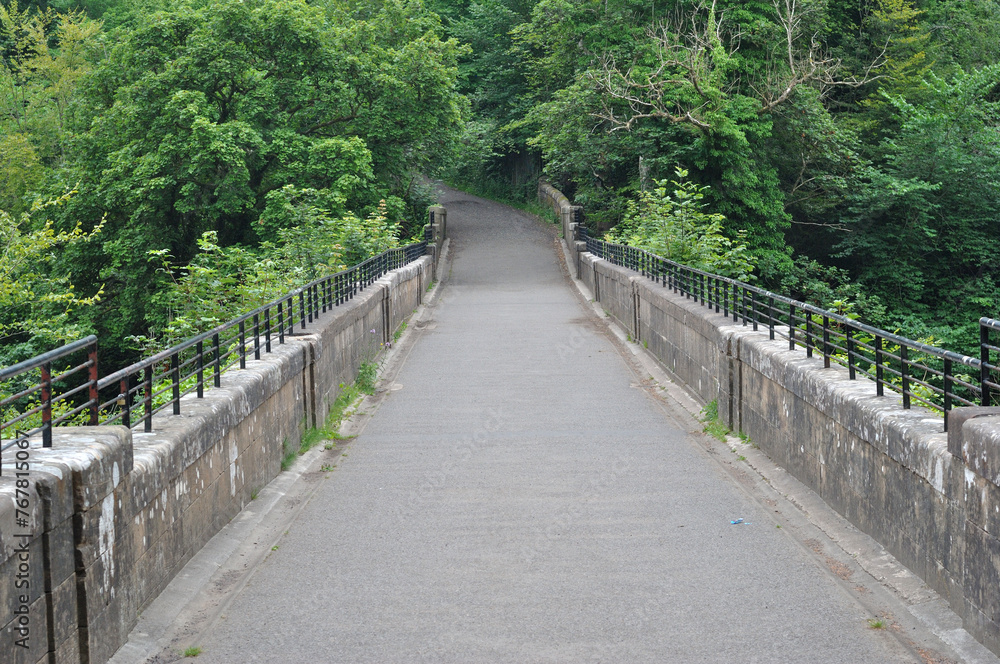 View along Deserted Old Stone Bridge across Deep Wooded Valley 