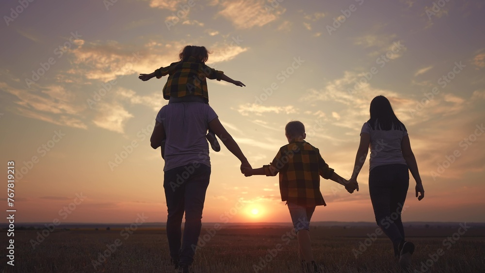 Fototapeta premium people in the park. big family silhouette walk at sunset. mom dad and daughters walk holding hands in the park. large family kid dream concept. parents and children walking back fun silhouette