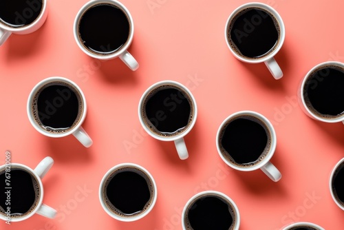 Mugs of black coffee in rows against peach background