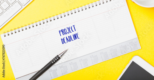 Project Deadline written in calendar on office table flat lay