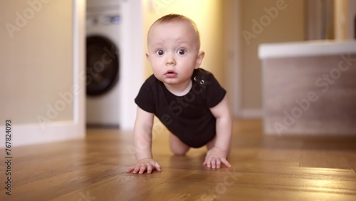 baby learns to crawl on the floor at home. happy family kindergarten kids concept. First steps, baby crawling front view . baby learns to crawl to explore the world around him dream