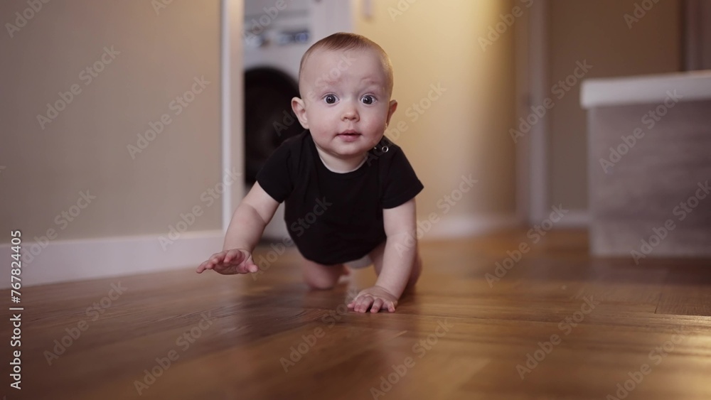 baby learns to crawl on the floor at home. happy family kindergarten kids concept. First steps, baby crawling front view . baby learns to crawl to explore the world around dream him baby learns to crawl on the floor at home. happy family kindergarten kids concept. First steps, baby crawling front view . baby learns to crawl to explore the world around dream him