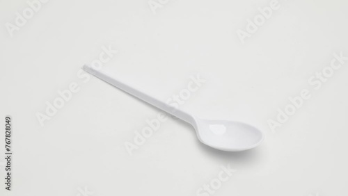 Plastic disposable spoon rotates on a white background.