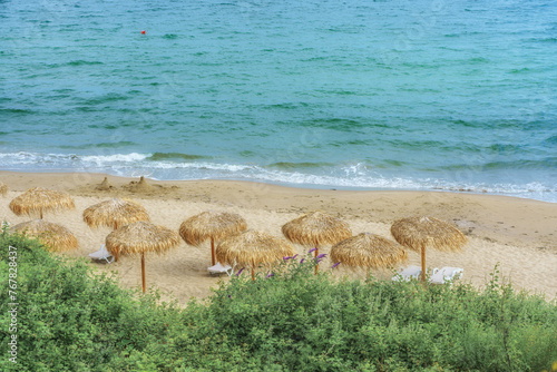 Holidays on the seaside. The beach straw parasols and lounge chairs on sandy beach. Calm and tranquility.