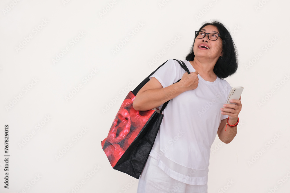 Closeup shot of Asian woman facing up while her hand busy holding smartphone and big red shopping bag Closeup shot of Asian woman facing up while her hand busy holding smartphone and big red shopping bag
