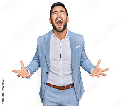 Young hispanic man wearing business jacket crazy and mad shouting and yelling with aggressive expression and arms raised. frustration concept.