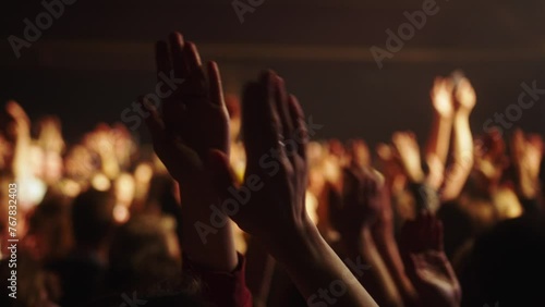 Cheering hands at a concert in front of a large stage in the spotlight close-up photo