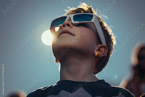 A young boy safely looks at a total eclipse while wearing protective glasses.