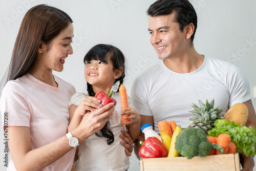 Family Joy in Healthy, happy asian family promoting healthy lifestyle smile father, mother and daughter behind a wooden crate with fresh fruits and vegetables, nutrition and wellness, grocery stores