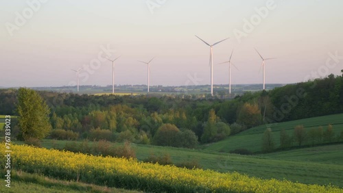 Rotating wind turbines in the wind between fields in spring photo