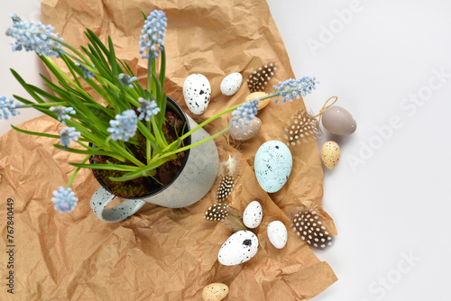 Easter eggs and light blue muscari flowers in cup on a white table. Easter still life. Top view