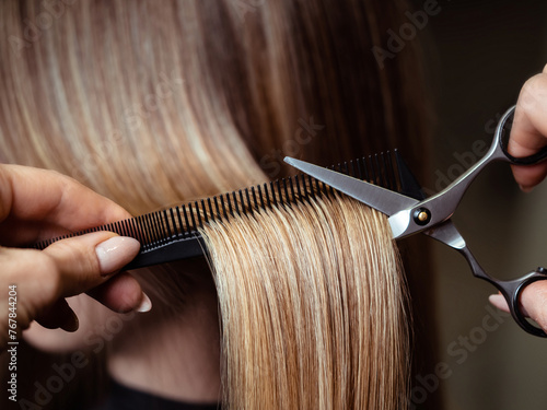 Hairdresser trimming light hair with scissors