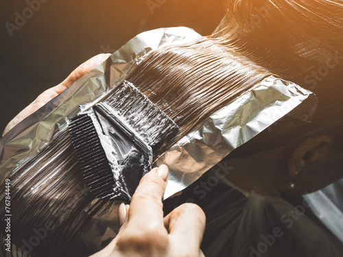 Hairdresser is applying bleaching powder on woman's hair