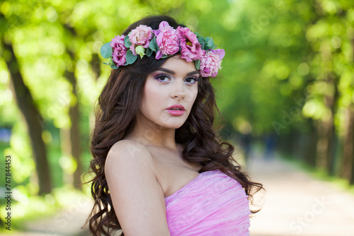 Lovely young adult lady with with long hair, make-up and pink flower in spring park. Beauty woman portrait