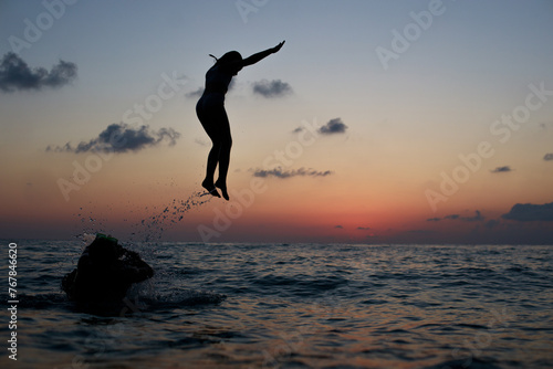 Happy family on sea beach. Happy vacation and holidays concept. Young girl jumping in the sea