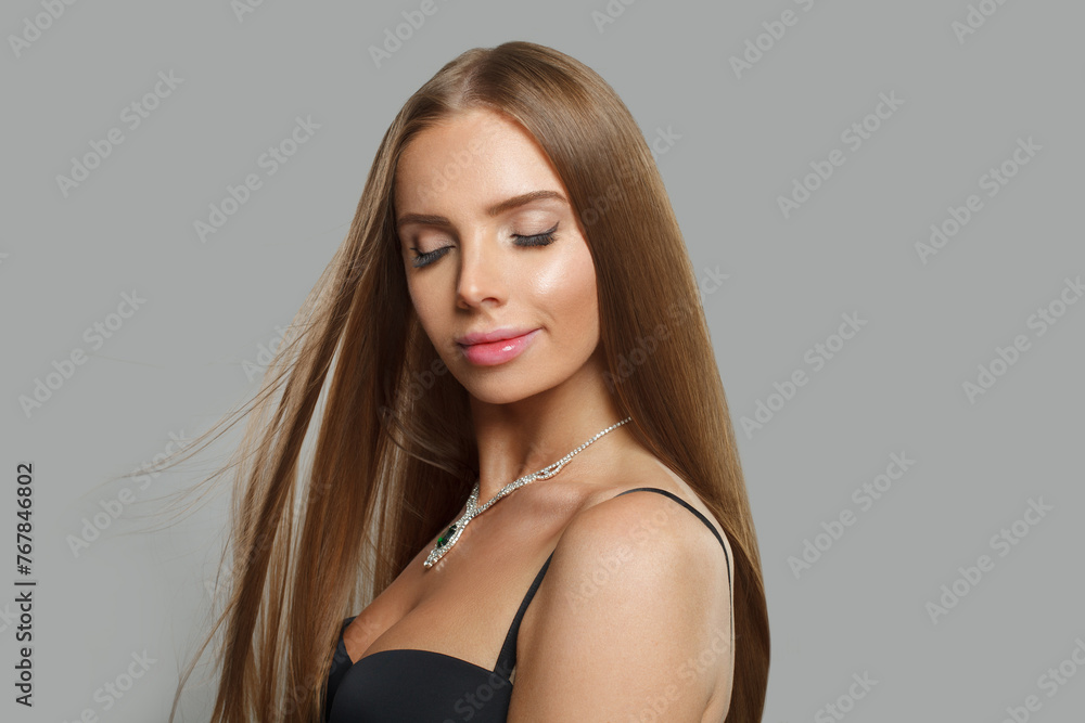 Young woman with makeup wearing jewelry necklace with sapphire and diamond on grey background