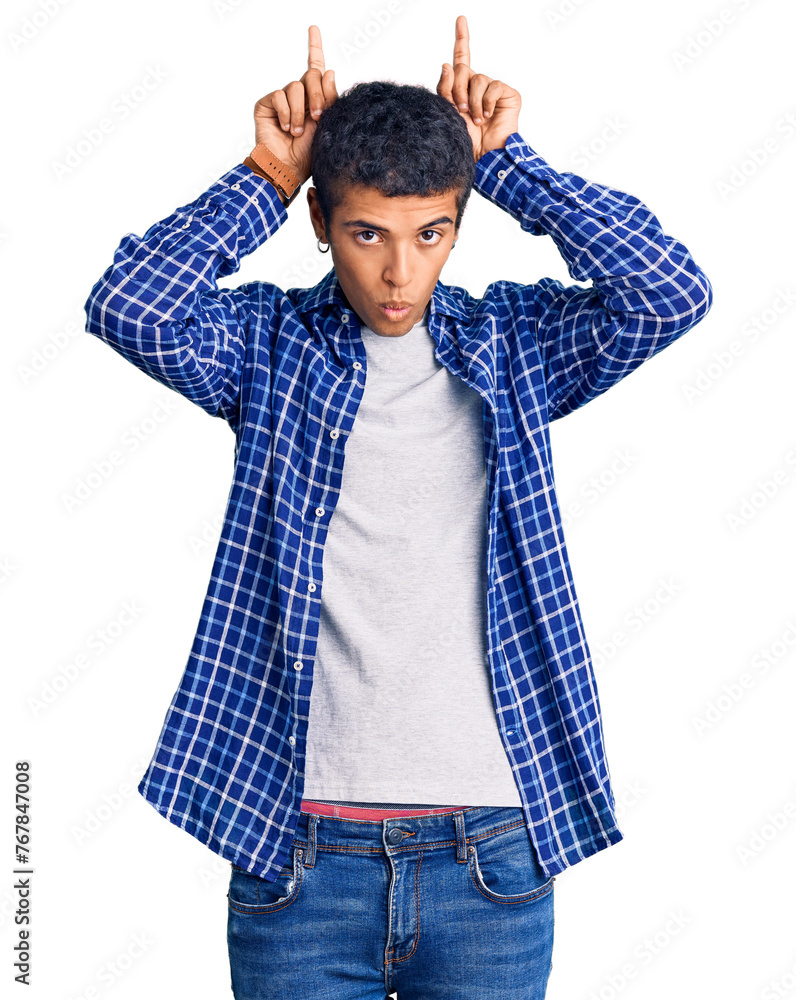 Young african amercian man wearing casual clothes doing funny gesture with finger over head as bull horns Young african amercian man wearing casual clothes doing funny gesture with finger over head as bull horns