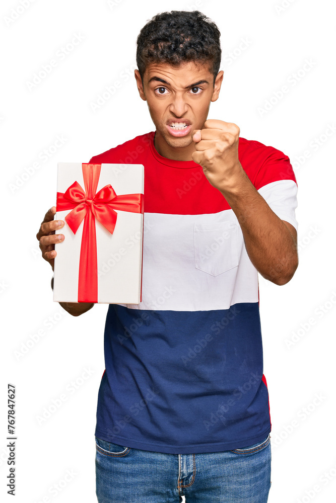 Young handsome african american man holding gift annoyed and frustrated shouting with anger, yelling crazy with anger and hand raised Young handsome african american man holding gift annoyed and frustrated shouting with anger, yelling crazy with anger and hand raised