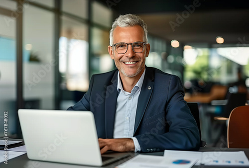 Smiling Mature Businessman Working on Laptop at Desk © sssheina