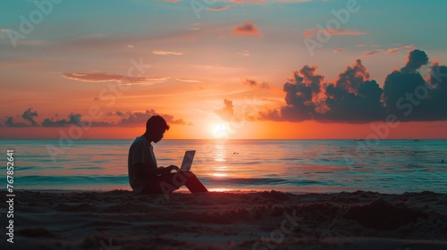 Silhouette of a man sitting on the beach using a laptop with a beautiful ocean sunset in the background.