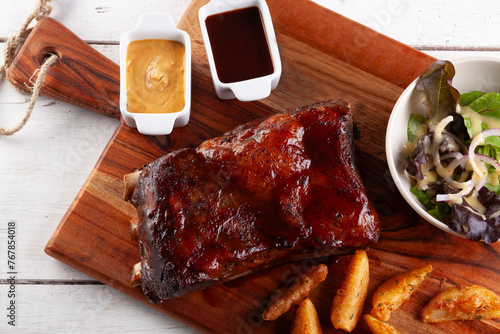 Grilled pork rib with potato wedges and sauces..