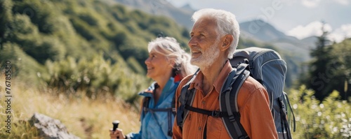 Seniors hiking in the mountains with backpacks, sunny day.