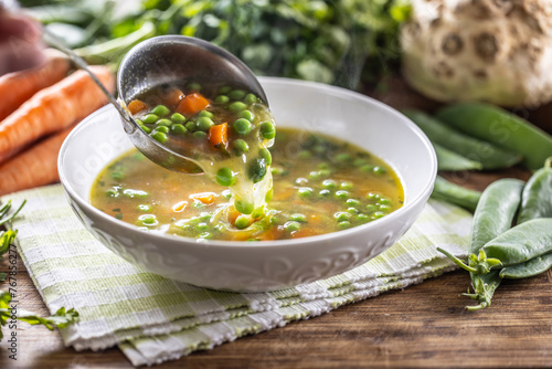 Healthy vegetable soup from fresh spring vegetable Scooping up hot soup with a ladle