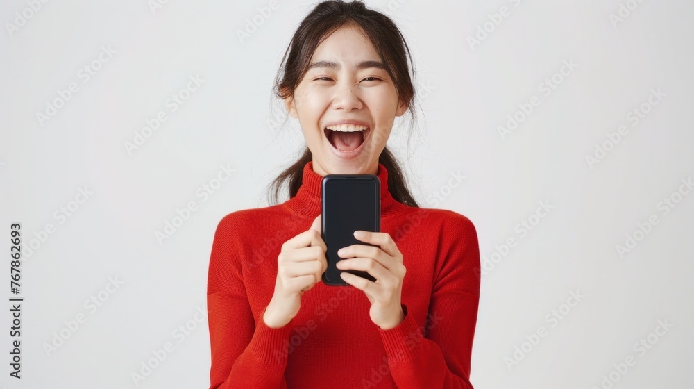 Asian woman delighted with good news on smartphone, celebrating positive surprise. Asian woman delighted with good news on smartphone, celebrating positive surprise.