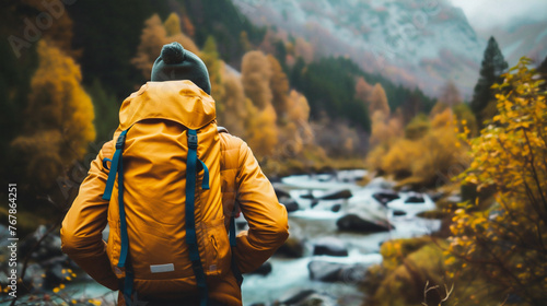 Hiker with backpack on the background of a mountain river and autumn forest