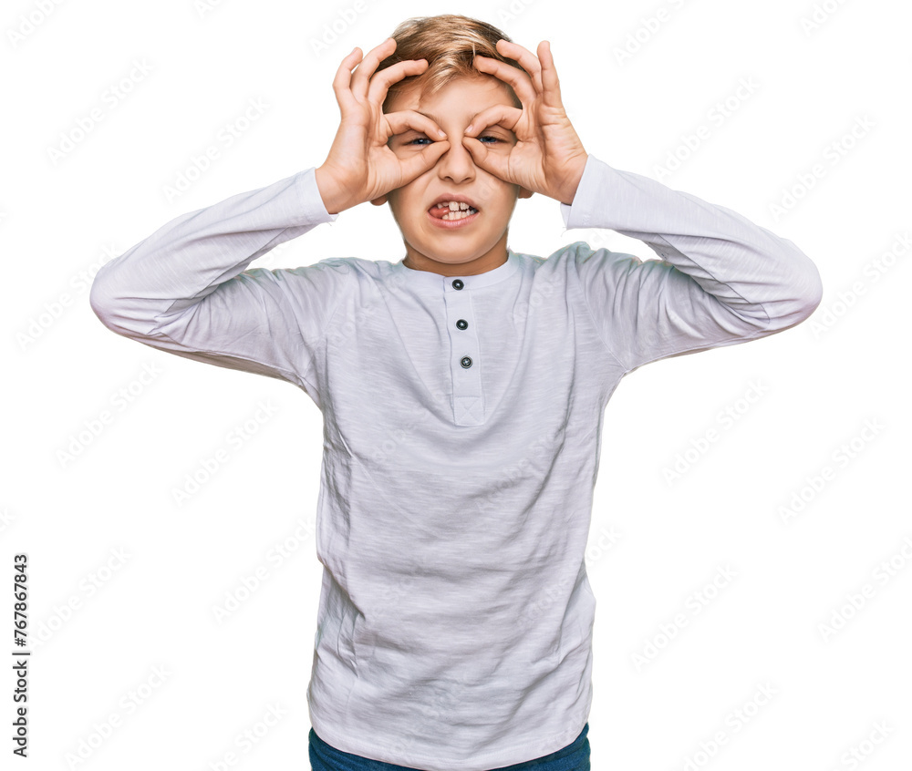 Little caucasian boy kid wearing casual clothes doing ok gesture like binoculars sticking tongue out, eyes looking through fingers. crazy expression. Little caucasian boy kid wearing casual clothes doing ok gesture like binoculars sticking tongue out, eyes looking through fingers. crazy expression.