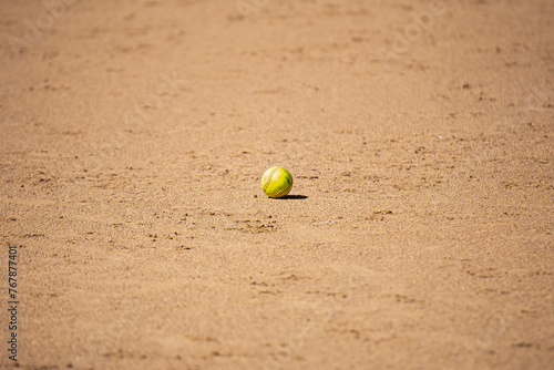 Softball with harsh shadow in the sand (ID: 767877401)
