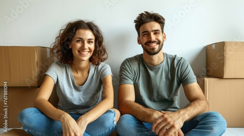 Happy couple sitting on the floor among moving boxes in a new home.