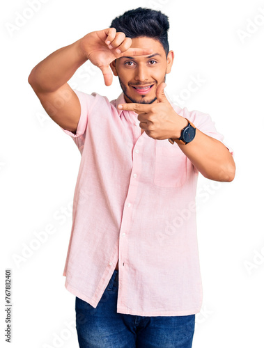 Handsome latin american young man wearing casual summer shirt smiling making frame with hands and fingers with happy face. creativity and photography concept.